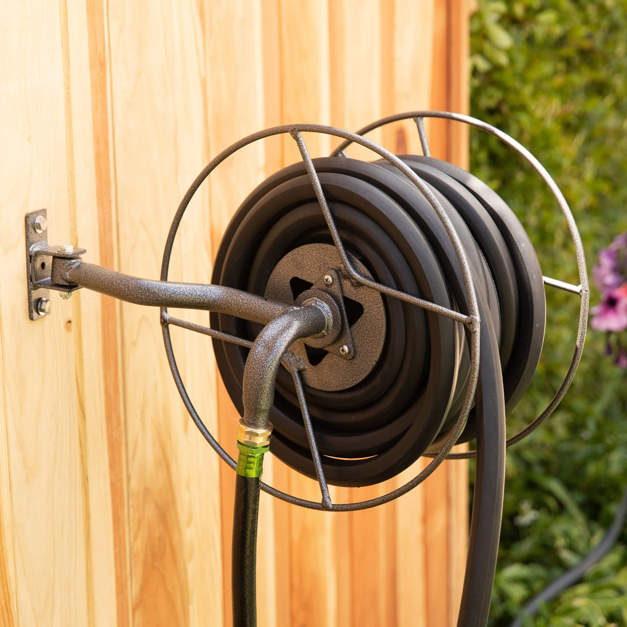 قرقره شلنگ جمع‌کن دیواری نصب شده روی دیوار حیاط